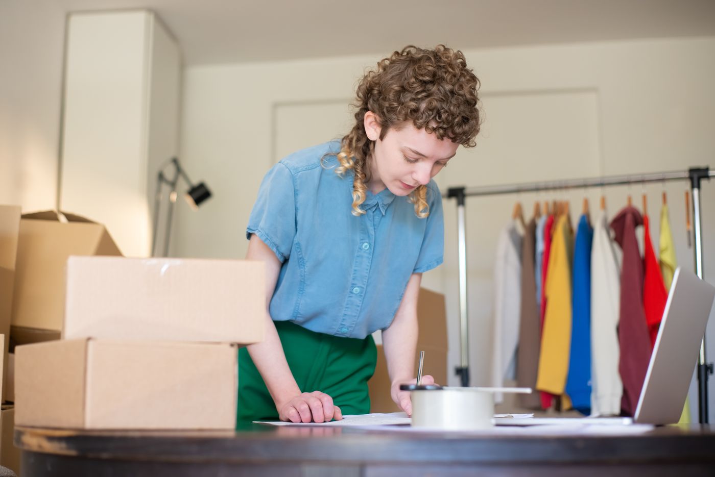 Entrepreneur preparing online shop orders with boxes and a laptop