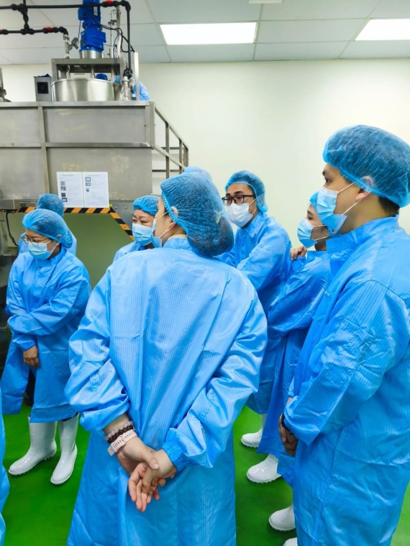Visitors in full cleanroom attire viewing a stainless steel mixing vessel during the Nutrizens facility tour