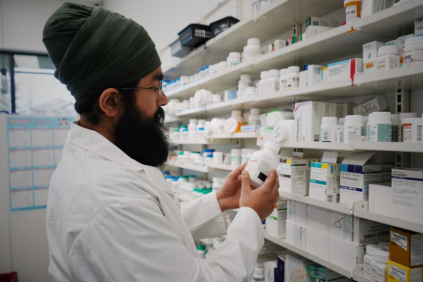 Pharmacist checking a product on stocked pharmacy shelves